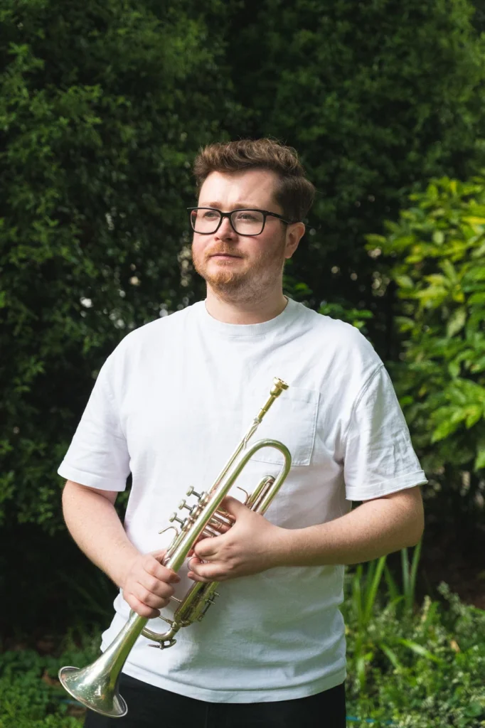 Man staring wistfully into the distance holding a trumpet